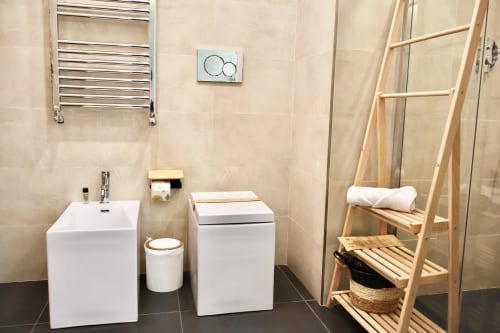 Bagno moderno in Taga Rooms Catania con lavabo bianco, WC, scaletta in legno, scaldasalviette e doccia