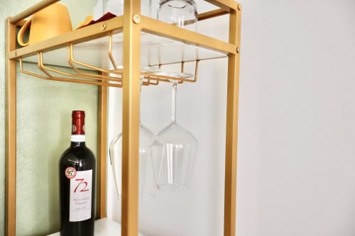 Portabottiglie in legno con bottiglia di vino rosso e calice sospeso nella camera dell'hotel Taga Rooms Catania