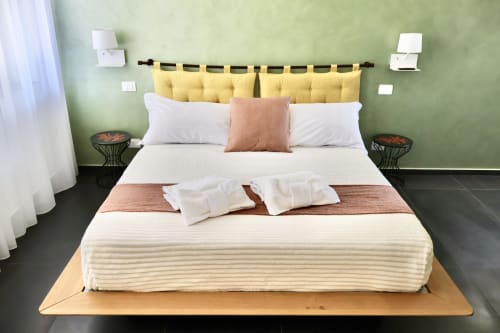 Camera deluxe presso Taga Rooms Catania con testata gialla, biancheria bianca e servizi moderni