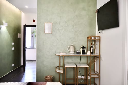 Camera moderna di Taga Rooms Catania con pareti verdi, scrivania in legno, TV a schermo piatto e vista sulla città