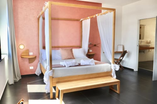 Elegante letto a quattro colonne con tende bianche nella camera Superior di Taga Rooms, Catania, parete accent in corallo