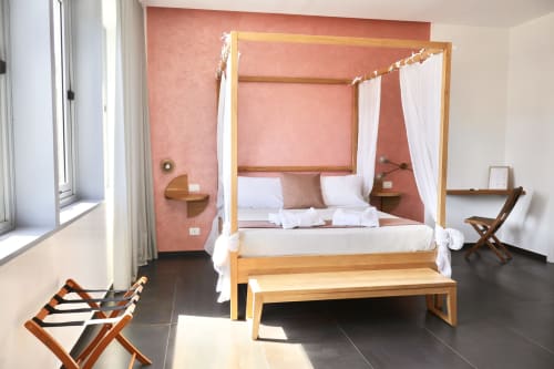 Camera superior presso Taga Rooms a Catania con letto a quattro colonne in legno, tende bianche, parete accent color corallo e vista sulla città