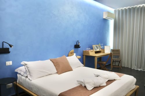 Camera moderna presso Taga Rooms Catania con parete accent blu, letto matrimoniale, scrivania e climatizzatore