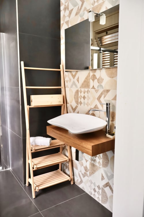 Bagno moderno di Taga Rooms Catania con lavabo in legno, scaffale a scaletta, rivestimento in piastrelle decorate e nero