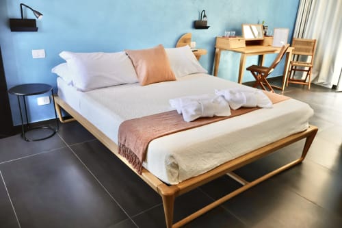 Camera deluxe presso Taga Rooms a Catania con letto in legno, biancheria bianca, parete azzurra, scrivania e vista sulla città