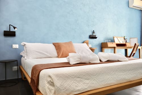Camera deluxe di Taga Rooms Catania con letto in legno, biancheria bianca, cuscino marrone e pareti azzurre con zona di lavoro