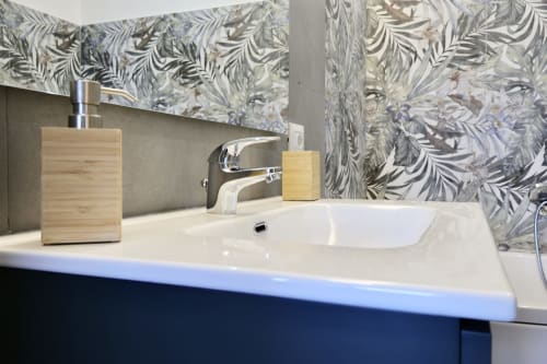 Lavabo moderno presso Taga Rooms Catania con bacino bianco, rubinetto cromato, accessori in legno e parete con piastrelle decorate