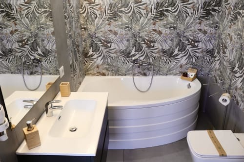 Bagno moderno a Taga Rooms Catania con vasca blu curva, lavabo bianco, piastrelle decorative e accessori contemporanei