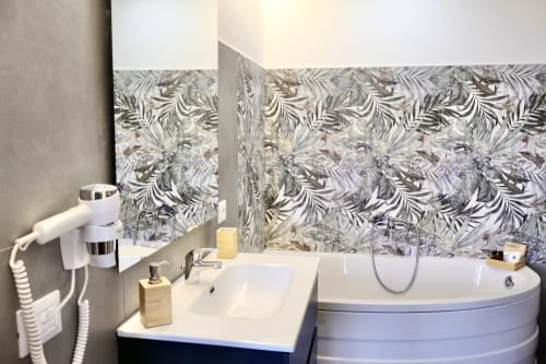 Bagno moderno presso Taga Rooms a Catania con parete a piastrelle decorate, lavabo bianco, vasca rotonda e servizi