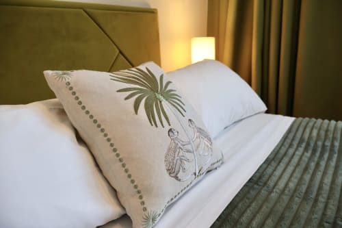 Cuscini decorativi sul letto della camera Taga Rooms Catania con testata in olivo e illuminazione calda