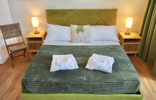 Camera moderna presso Taga Rooms Catania con testata verde, comodini gemelli, illuminazione calda e vista sulla città