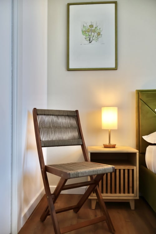 Angolo camera moderna a Taga Rooms Catania con sedia in legno, comodino, lampada e arte botanica alle pareti