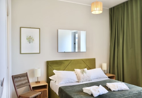 Camera moderna di Taga Rooms Catania con testiera verde oliva, specchio con vista sulla città e arredi contemporanei