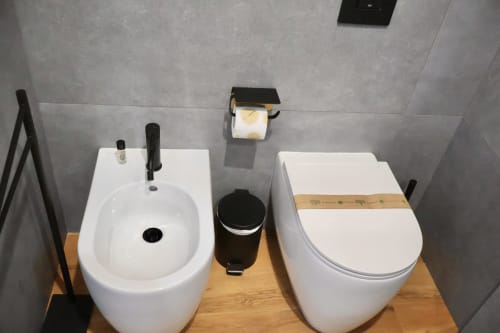 Moderni sanitari presso Taga Rooms Catania: bidet, wc e cestino su pavimento in legno