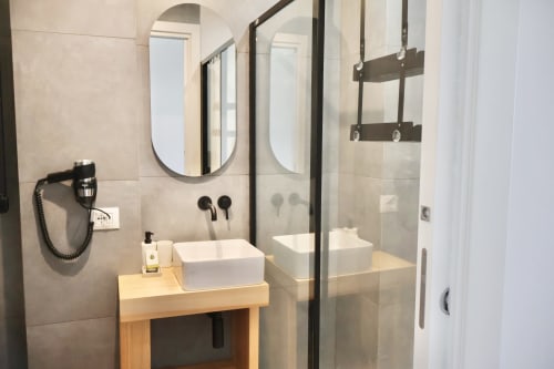 Bagno moderno presso Taga Rooms Catania con lavabo a coppa, specchio ovale e doccia walk-in con cornice nera