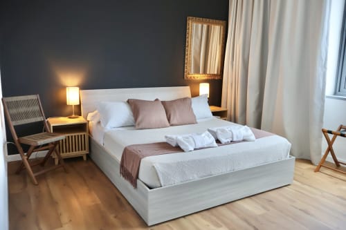 Camera moderna presso Taga Rooms a Catania con letto bianco, dettagli marrone, pavimenti in legno e vista sulla città