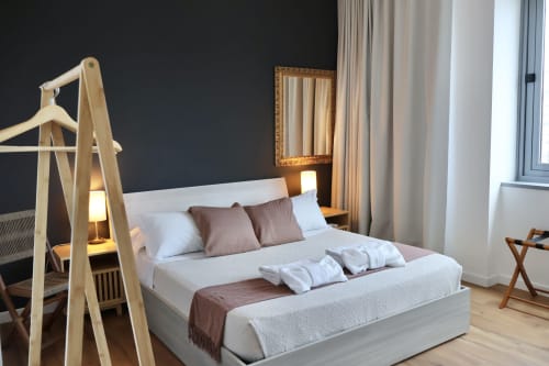 Camera moderna presso Taga Rooms Catania con letto a baldacchino in legno, biancheria beige e vista città dalla finestra