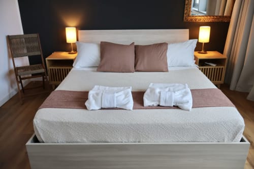 Camera da letto elegante presso Taga Rooms Catania con letto king, cuscini marrone, comodini gemelli con illuminazione calda e vista città