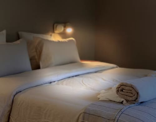 Quarto aconchegante na Quinta Do Carril com cama bem arrumada, almofadas, toalha dobrada e iluminação ambiente quente em Reguengo, Portugal