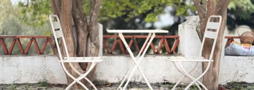 Área de estar ao ar livre da Quinta Do Carril B&B em Reguengo com cadeiras brancas dobráveis e mesa sob árvores frondosas
