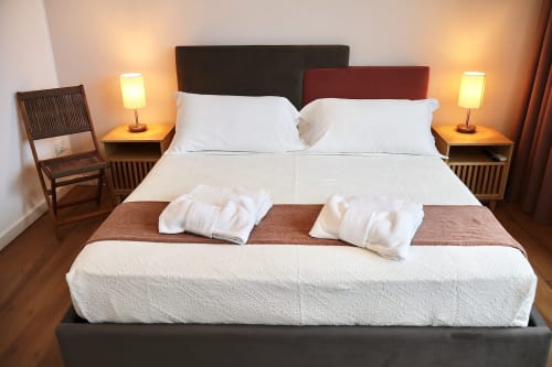 Taga Rooms Catania: Camera moderna con biancheria bianca, doppi capezzali, lampade laterali, sedia in legno e vista sulla città in questo BnB
