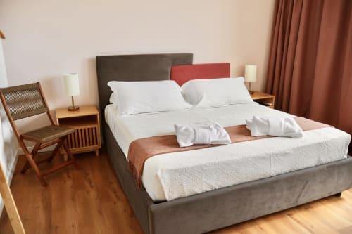 Camera moderna a Taga Rooms a Catania con letto king size, biancheria bianca, arredamento in legno e tende con vista sulla città