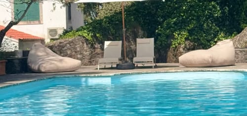 Zona de piscina da Quinta do Carril em Reguengo com espreguiçadeiras e muros de pedra rodeados de vegetação