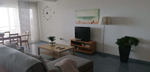 Sala de estar moderna com vista para o mar em A Casa da Xã, Ilha de Santa Maria, com TV, sofá, mesa de jantar e luz natural