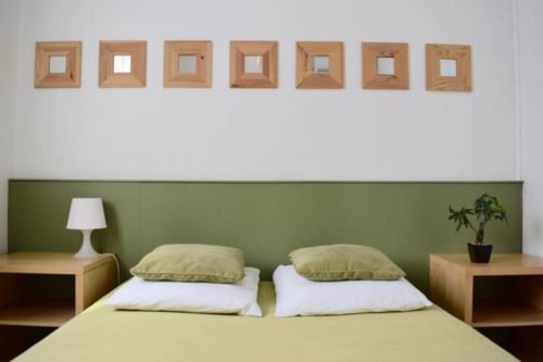 Modern hotel bedroom at Hôtel l'Orangeraie Lavandou with green headboard, twin beds, and wooden decor