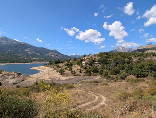 Vue sur le lac de montagne avec bâtiments dispersés et pics environnants à Calacuccia, Corse