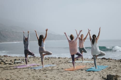 Cours de yoga en groupe sur la plage de la Bleu Guesthouse, France avec vue sur l'océan et les falaises