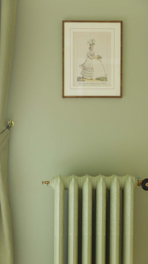 Illustration botanique encadrée sur mur vert pâle au-dessus d'un radiateur blanc dans la chambre d'hôtes de Gare Godillot Saint-Ouen-sur-Seine
