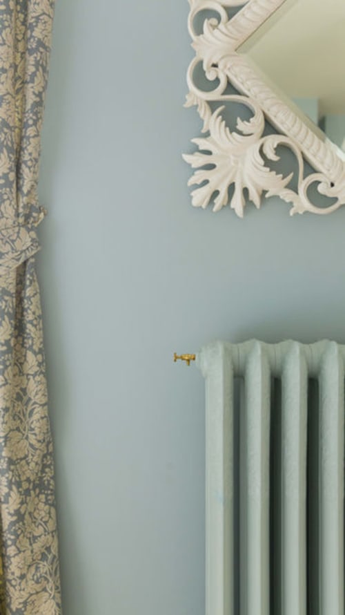 Coin chambre élégant à la Gare Godillot B&B : murs bleu pâle, corniche blanche ornementale, rideaux à motifs et blanc