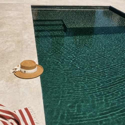 Sombrero de paja junto a la piscina verde de Casa Rural Finca El Olivar, Las Cuevas