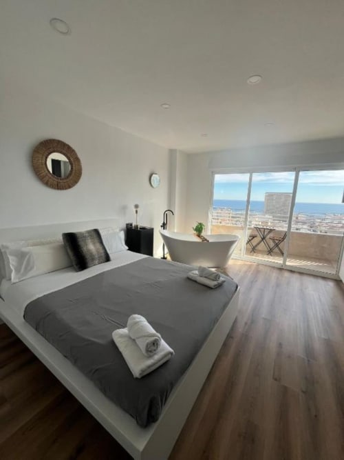Moderno dormitorio en ROILA360 Alicante con vista al mar, cama y bañera exenta