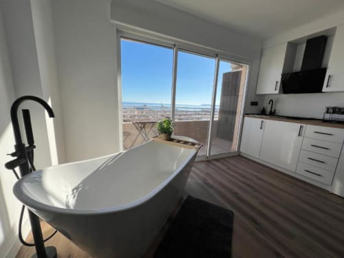 Baño moderno con bañera exenta, zona de cocina y vistas panorámicas de la ciudad en el hotel ROILA360 Alicante