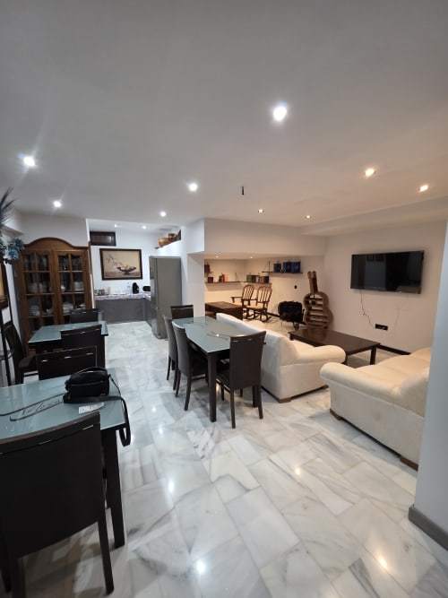 Área de estar moderna y diáfana en Hostal El Pasaje de Puente Genil con piso de mármol, mesa de comedor, sofás crema y