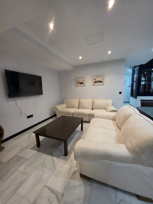 Sala moderna del Hostal El Pasaje en Puente Genil con sofás crema, mesa de madera oscura y televisor de pantalla plana