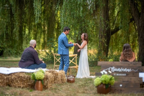 Couple exchanging rings at outdoor garden wedding ceremony under weeping willow trees at Domaine de Bafave in Périssac,