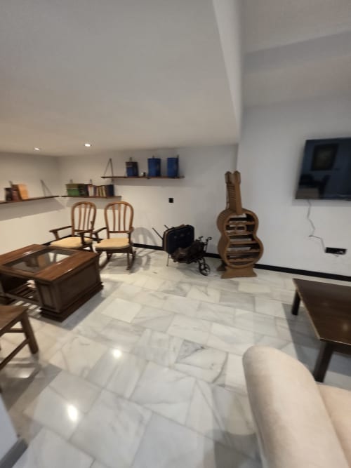 Moderna sala de estar en Hostal El Pasaje, Puente Genil, con pisos de mármol, muebles de madera, decoración de guitarra y paredes