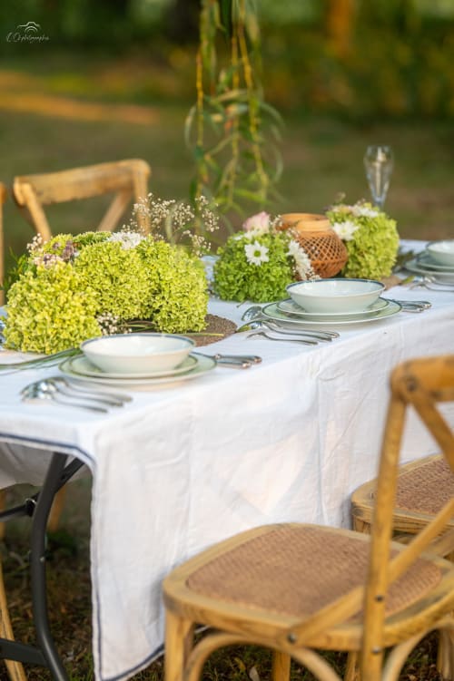 Elegant outdoor dining setup at Domaine De Bafave with lime green moss centerpieces, white linens, and wooden chairs