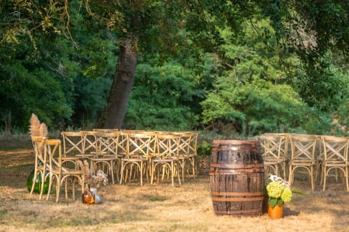 Rustic outdoor ceremony setup at Domaine De Bafave with wooden chairs, wine barrel, and forest backdrop in Périssac, France