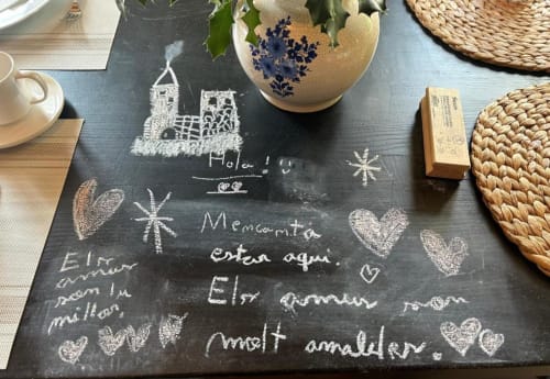 Pizarra con mensajes manuscritos y dibujos en Casa Tapiolas B&B en Molló, Girona