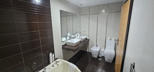 Modern bathroom at Hostal El Pasaje with dual sinks, toilet, bidet, and dark tile walls