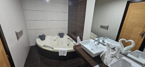 Luxury bathroom at Hostal El Pasaje in Puente Genil with Jacuzzi tub, dual sinks, towel swans, and modern tiling