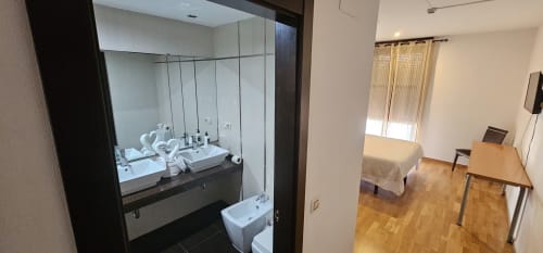 Modern bathroom with double sink vanity and bedroom view at Hostal El Pasaje, Puente Genil