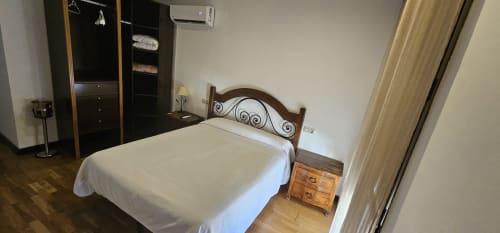 Double bedroom at Hostal El Pasaje in Puente Genil with wooden bed frame, white linens, and wardrobe
