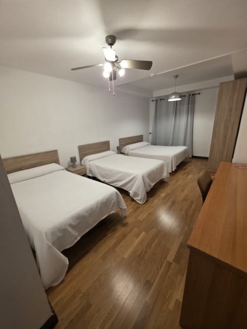 Habitación triple con tres camas individuales, suelo de madera, ventilador de techo y comodidades modernas en Hostal El Pasaje, Puente Genil