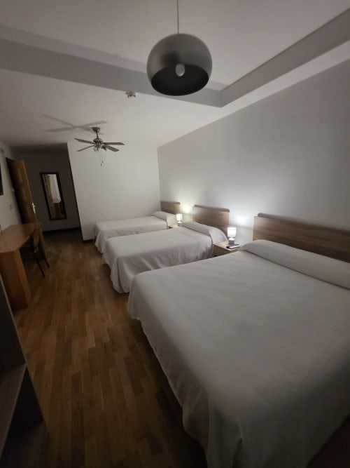 Habitación doble de Hostal El Pasaje en Puente Genil con dos camas, luz de techo moderna, ventilador, suelo de madera y ropa de cama blanca