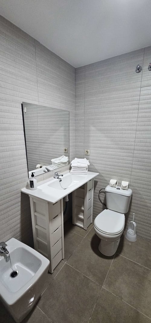 Baño moderno en Hostal El Pasaje de Puente Genil con lavamanos blanco, inodoro y paredes alicatadas